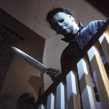 Micheal Meyers looking down from the stairs and holding a knife